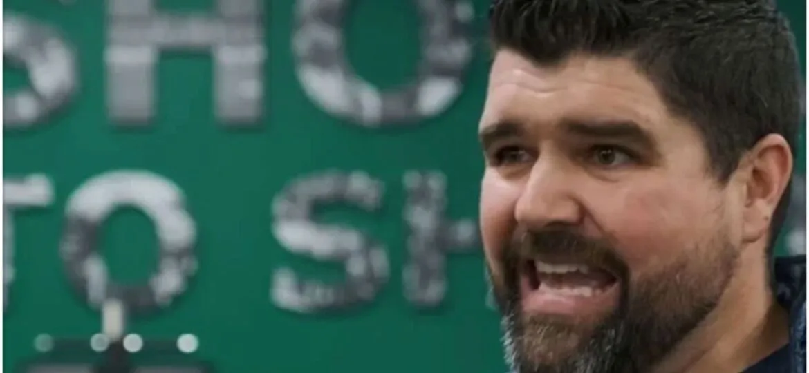 Nick Winkelman speaking energetically with a green background and partial text visible behind him.