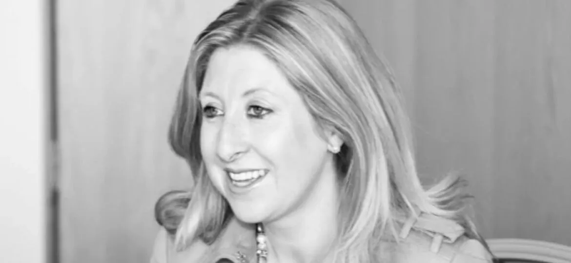 Black and white photo of a smiling woman with shoulder-length hair, wearing a necklace.