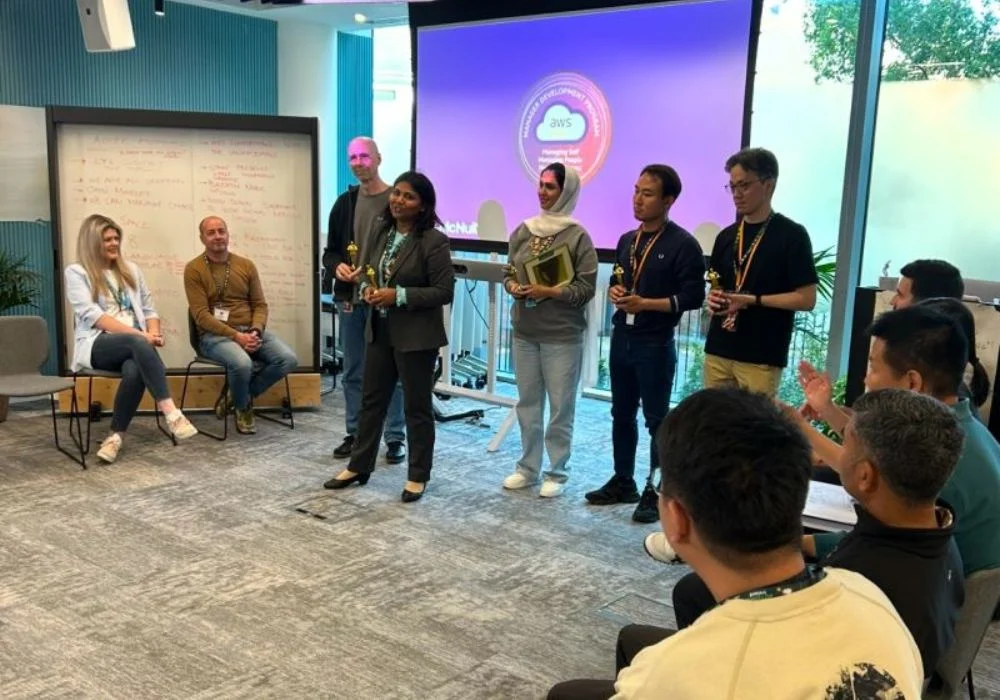 Group of AWS APAC leaders and McNulty Performance team during a leadership development session, with participants engaged and receiving awards in a workshop setting.